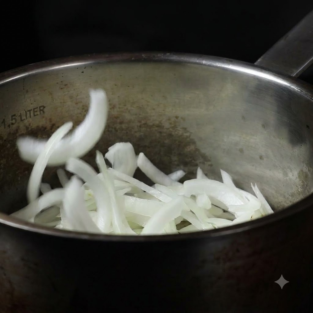 Sliced onions being dropped into a stainless steel cooking pot.