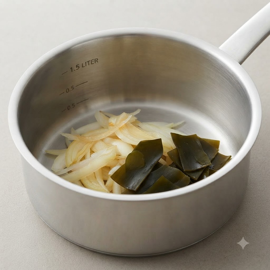 A cooking pot containing soft cooked onions alongside a folded kelp knot.