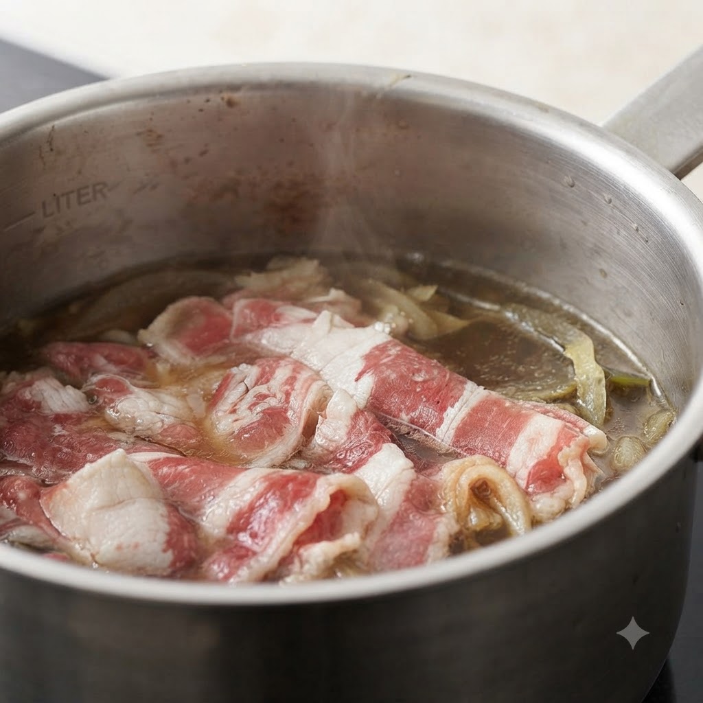 Minced ginger being added to a pot containing beef slices and onions in simmering broth.