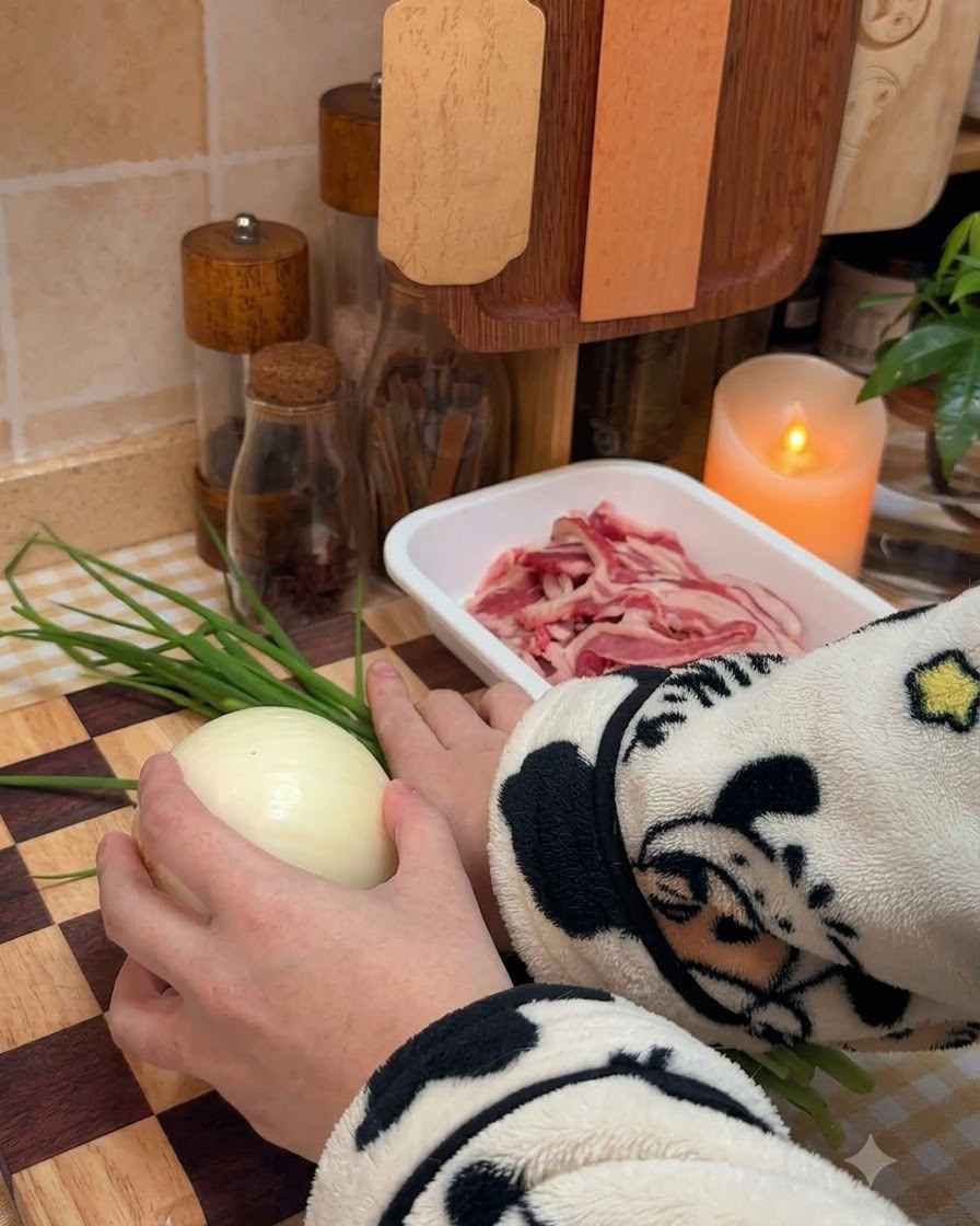 An onion being sliced into uniform strips on a wooden board.