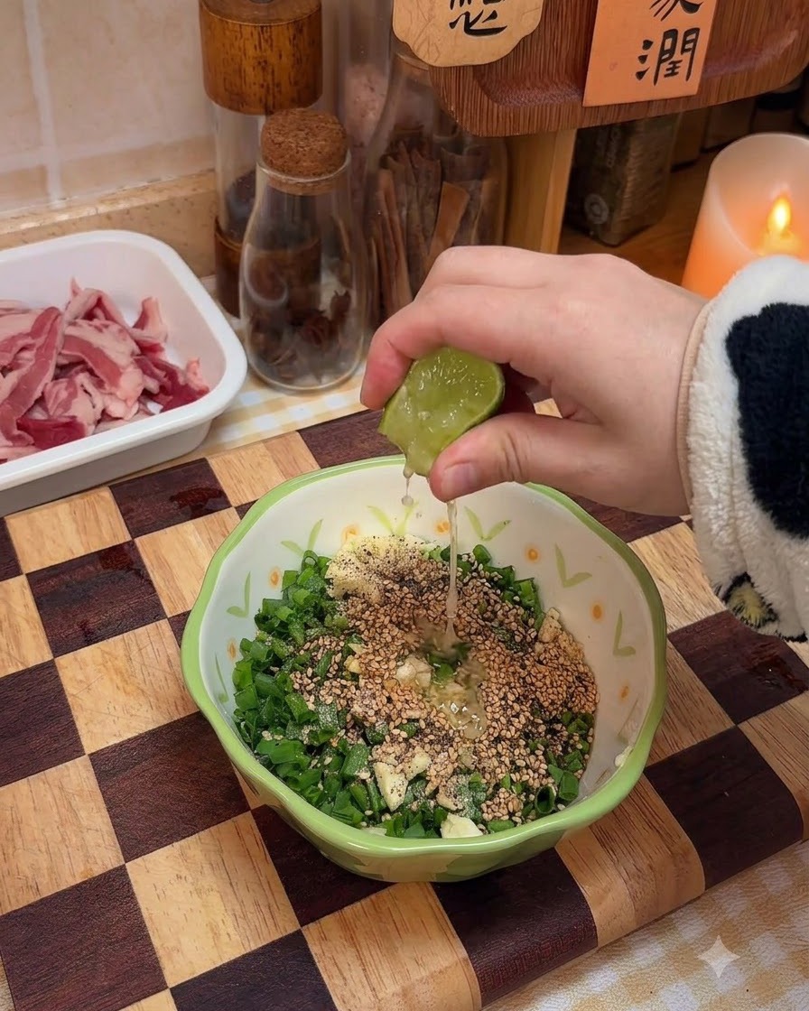 Fresh lime juice being squeezed into the bowl of scallion sauce ingredients.