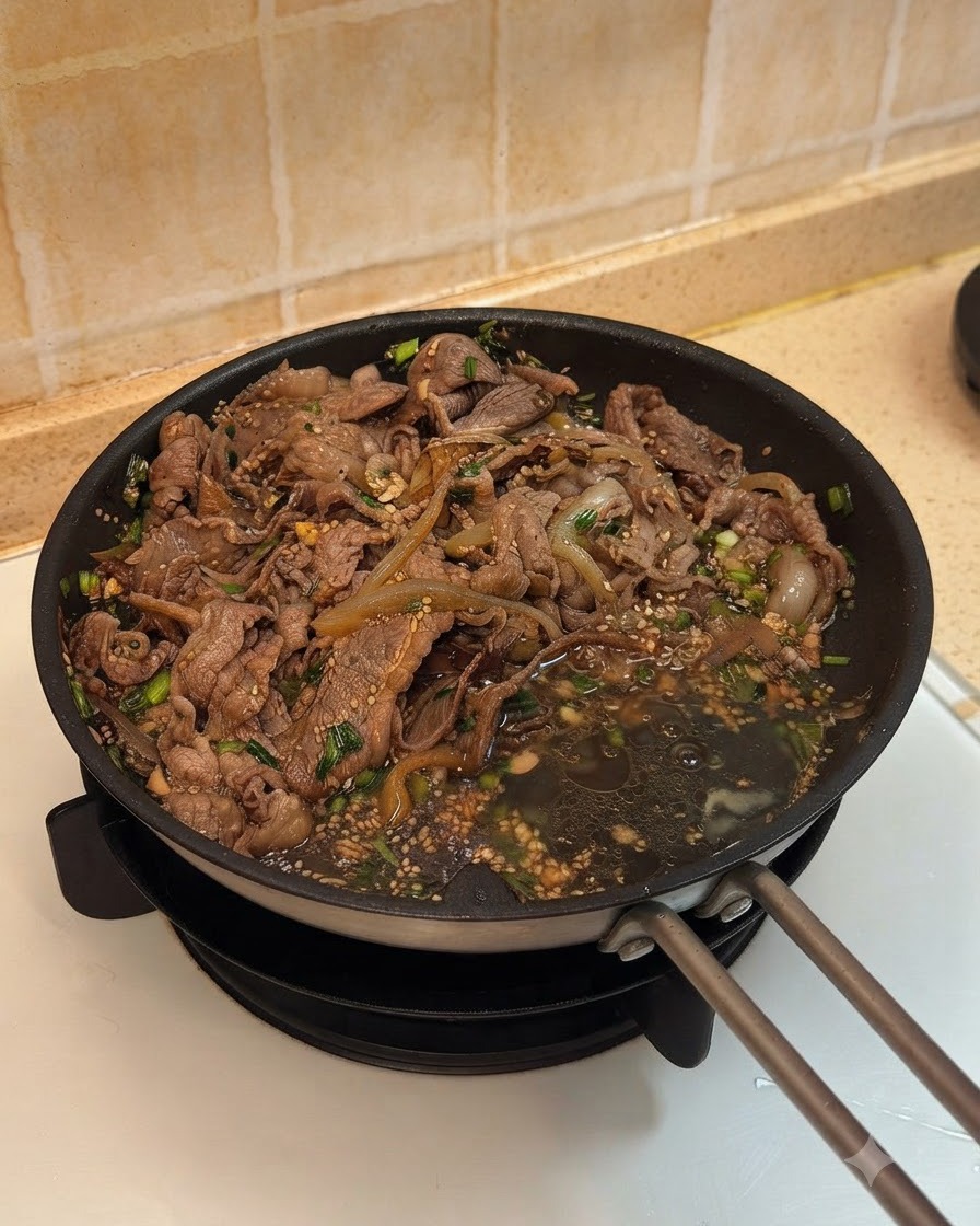 Two eggs cracked into the pan next to the cooked beef and onions in sauce.