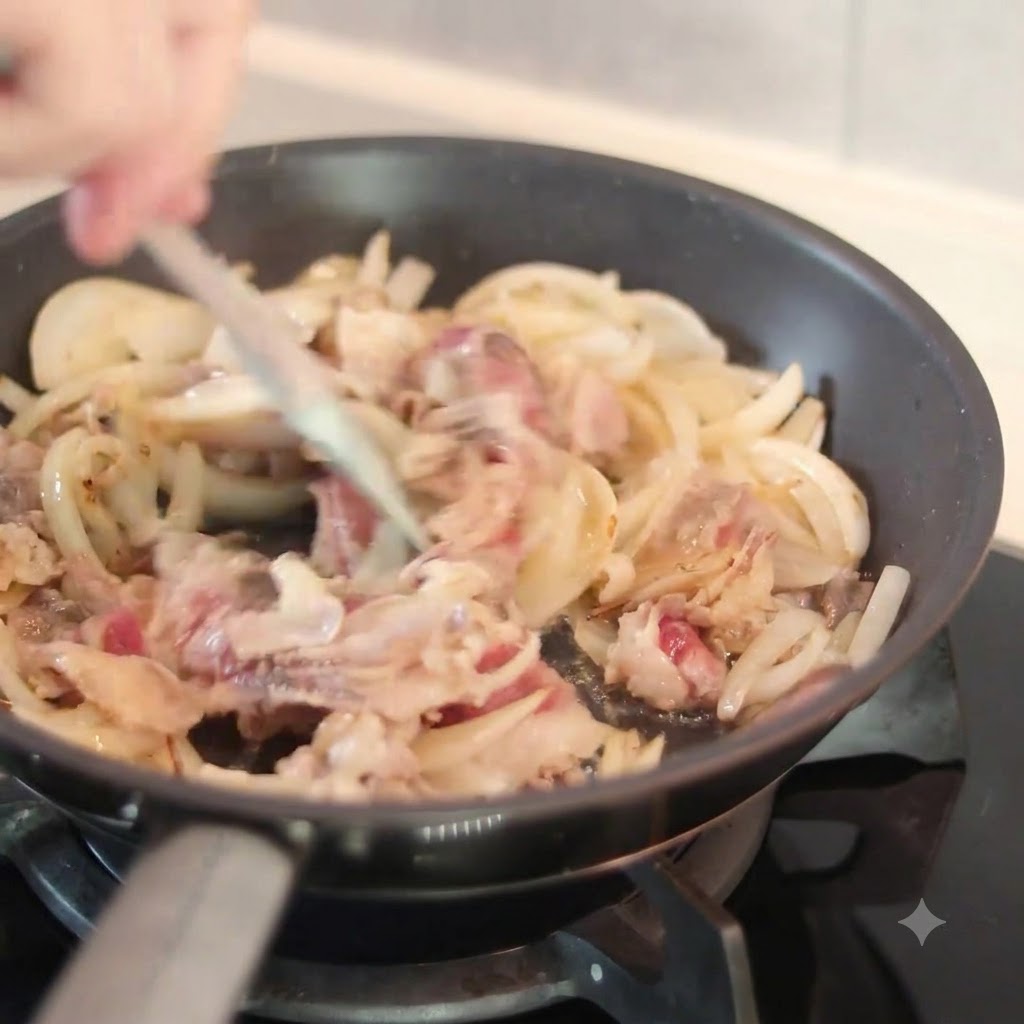 A dark sauce being poured from above into a hot frying pan containing sliced onions and beef pieces while being stirred with a spatula.