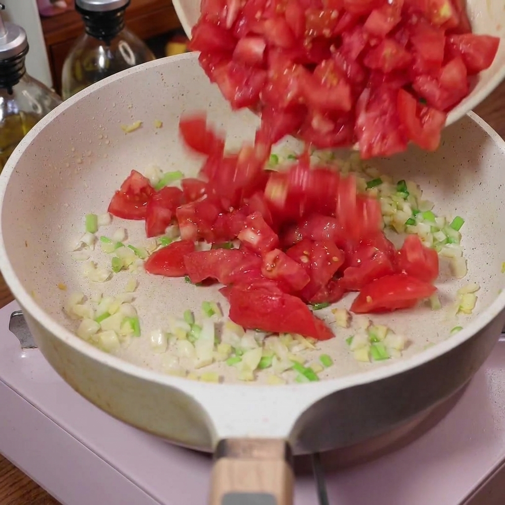 Diced tomatoes being poured into a pan with sautéed aromatics.