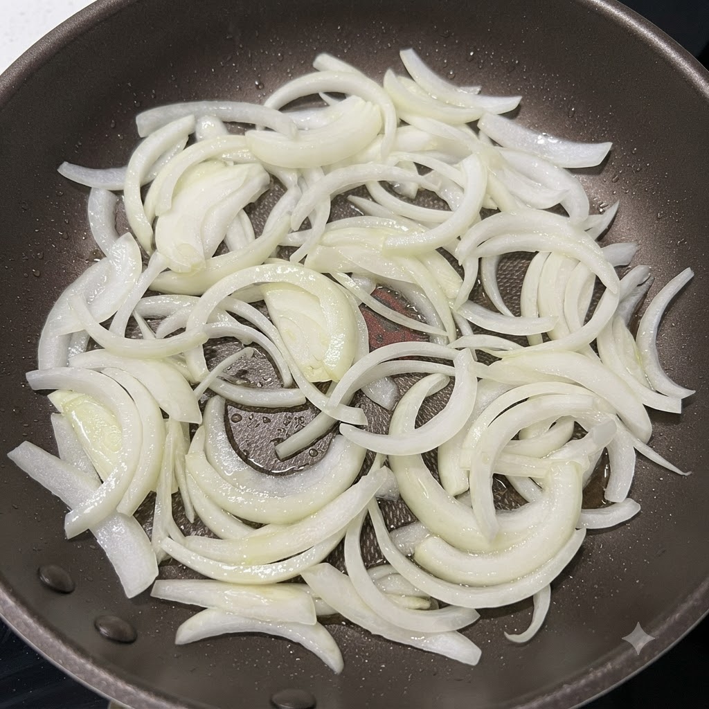 Onion strips being stir-fried in a hot pan until the edges are lightly browned.