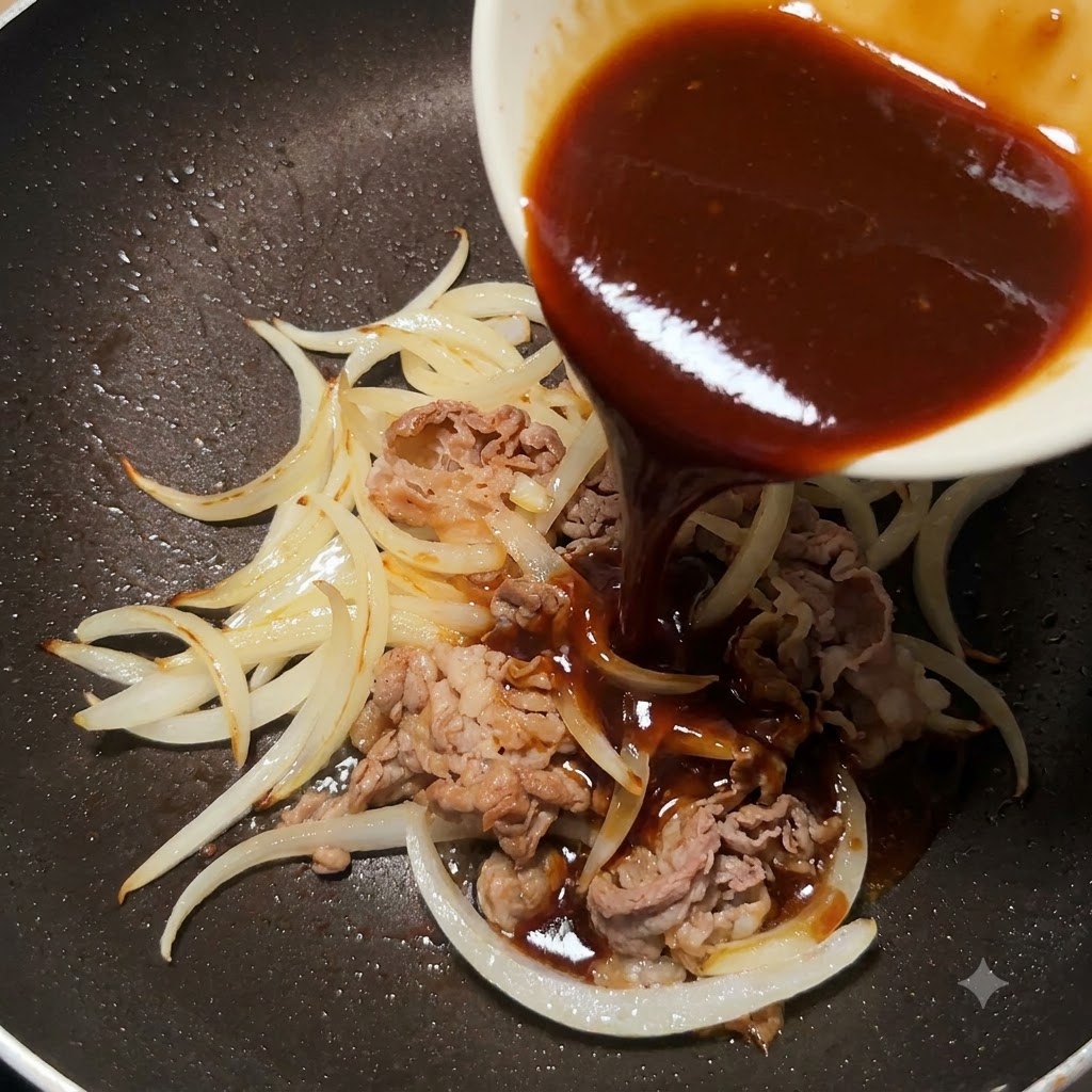 Thick teriyaki sauce being poured from a small white bowl into a pan with cooked sliced beef and sliced onions.