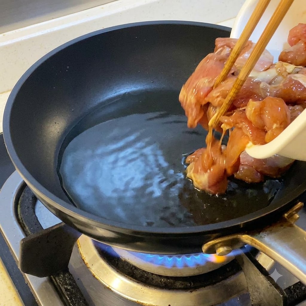 Marinated chicken pieces being added with chopsticks into a hot oiled frying pancite: 1.