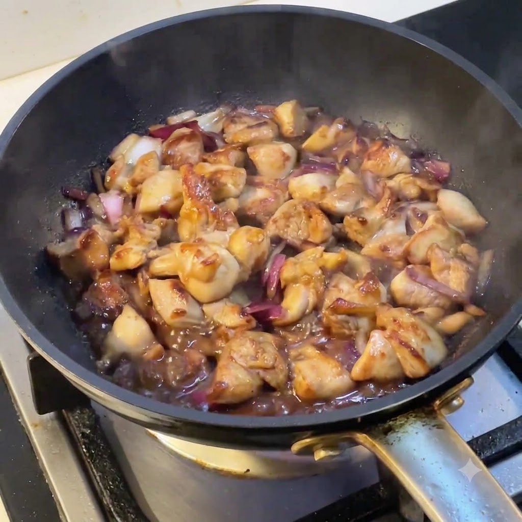 A pan filled with simmering chicken and onions as steam rises from the surface.