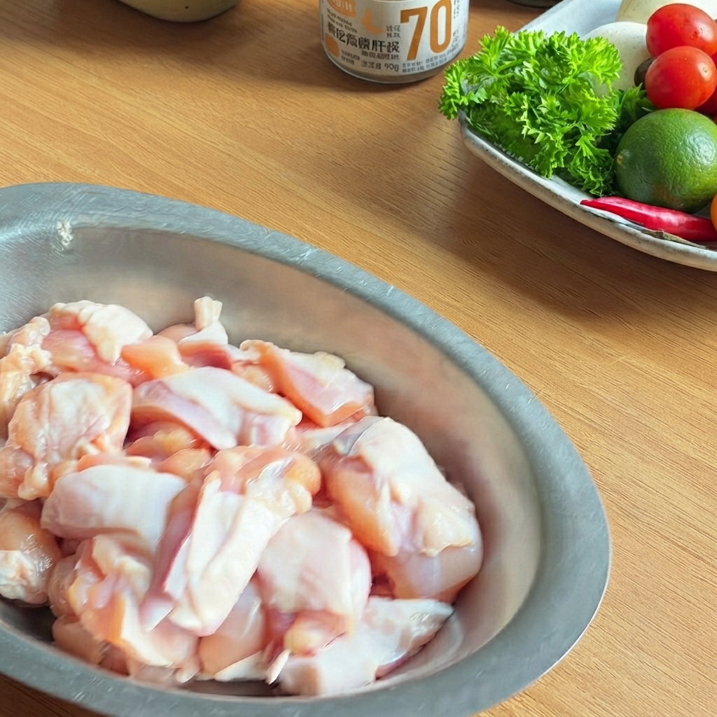 A metal bowl filled with raw chicken pieces seasoned with dark soy sauce, oyster sauce, and black pepper.