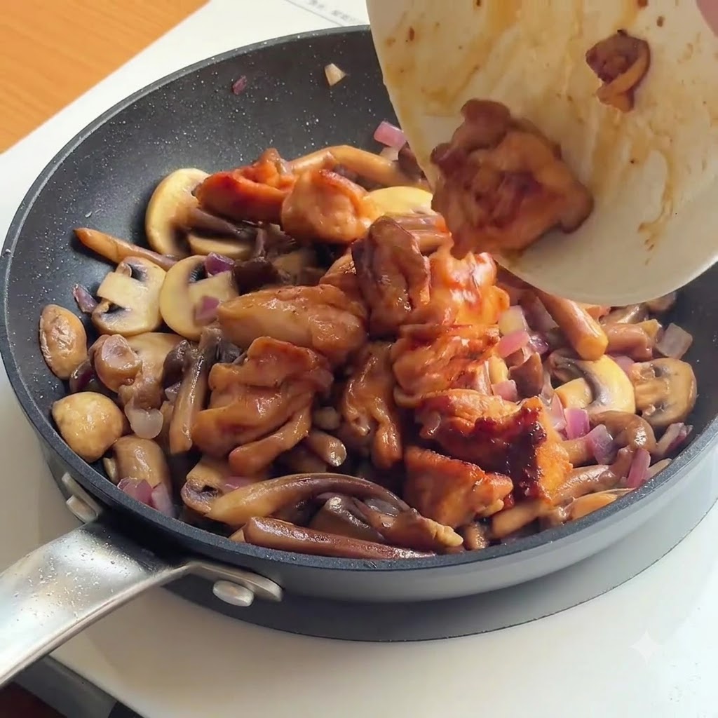 Cooked chicken and white rice being poured into a pan filled with sautéed mushrooms and onions.