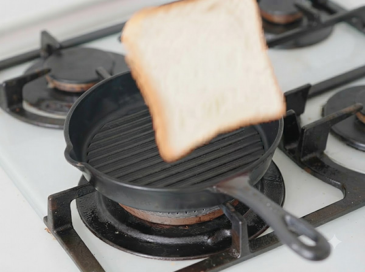 A single slice of bread sitting inside a black grill pan with cheese on top.
