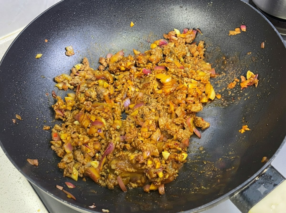 Milk being incorporated into the curry and meat sauce inside the pan.