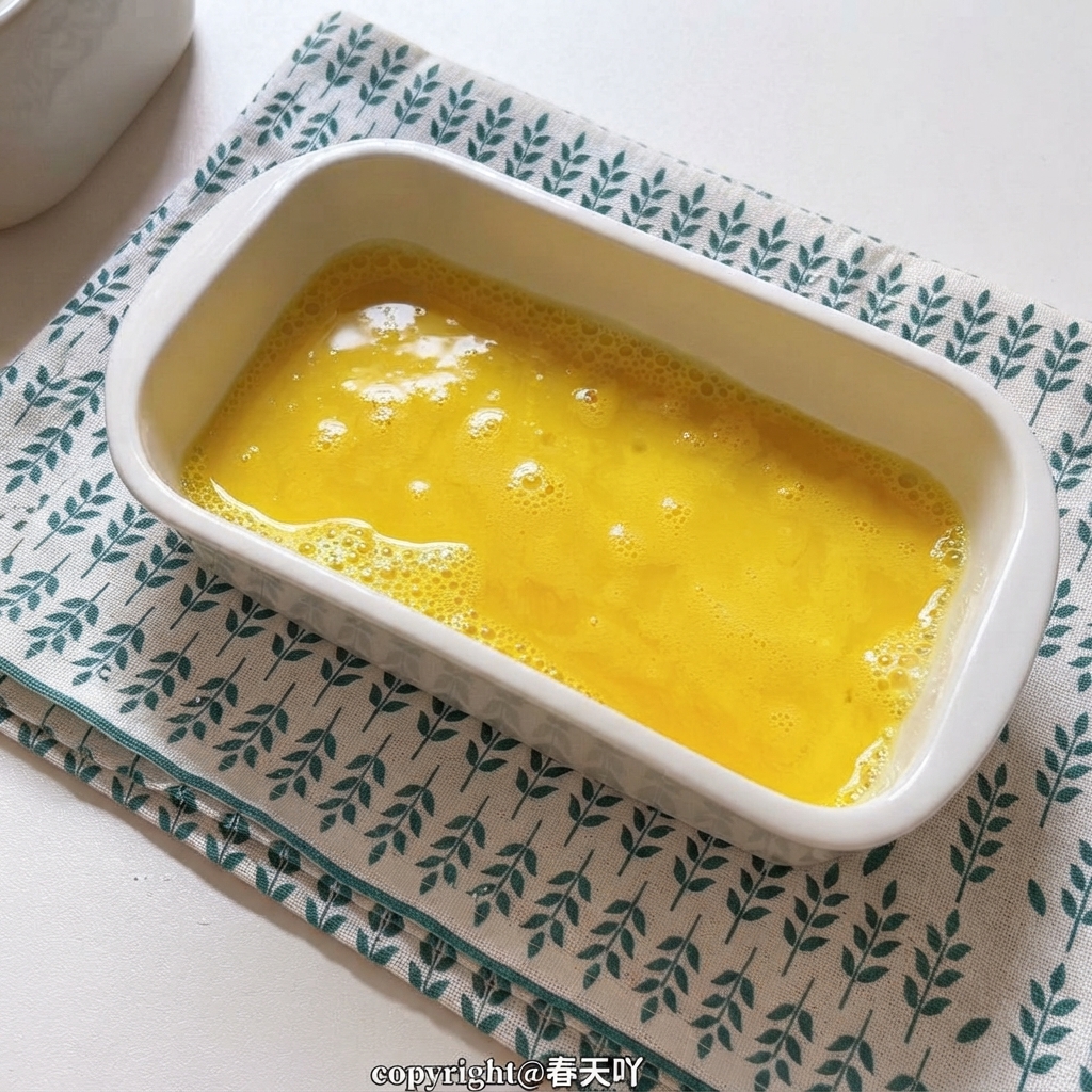 A white ceramic dish filled with golden yellow whisked eggs.