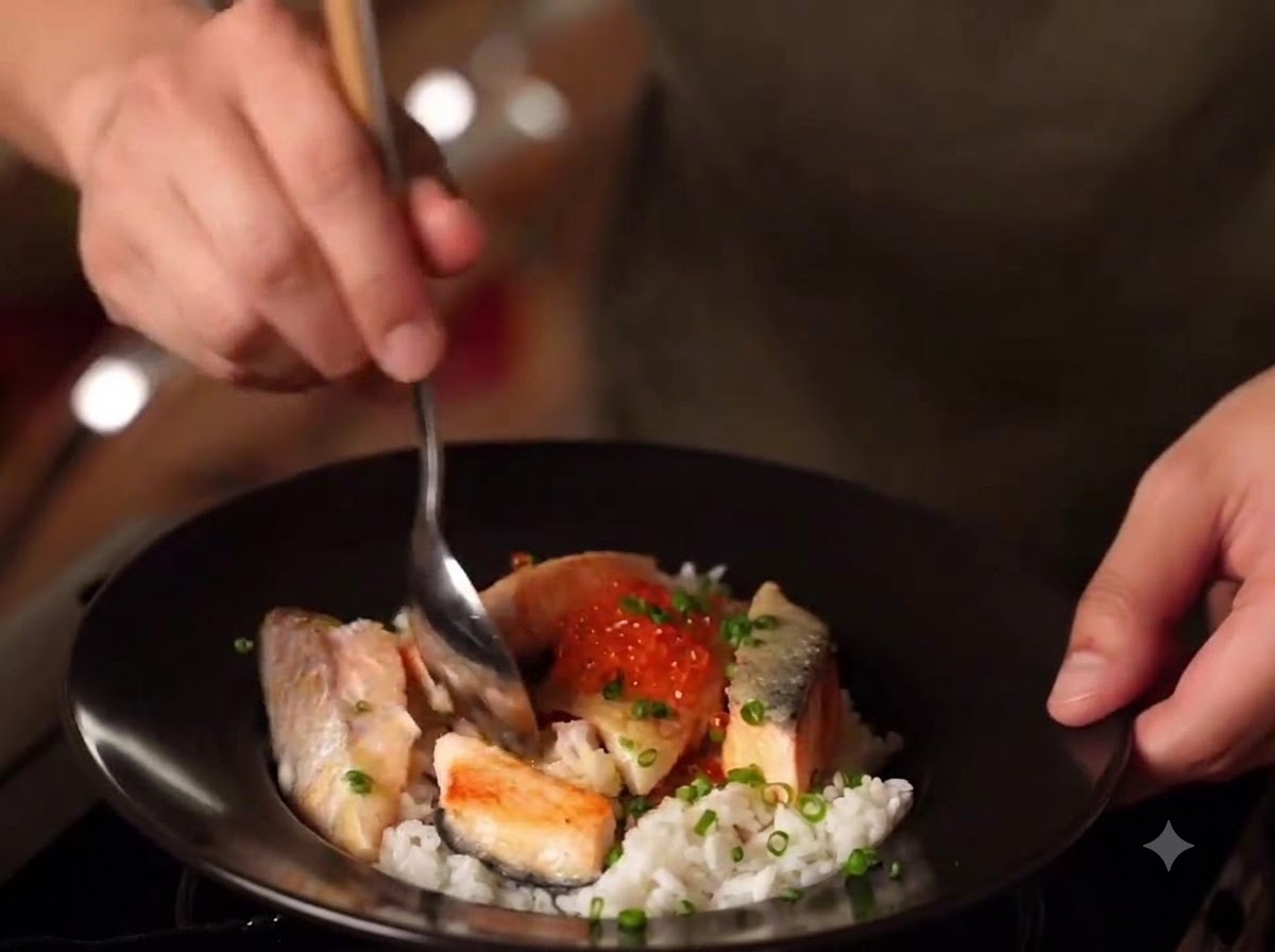 A close-up of a finished bowl of Miso Salmon Oyakodon with rice, seared salmon, salmon roe, and green onions.