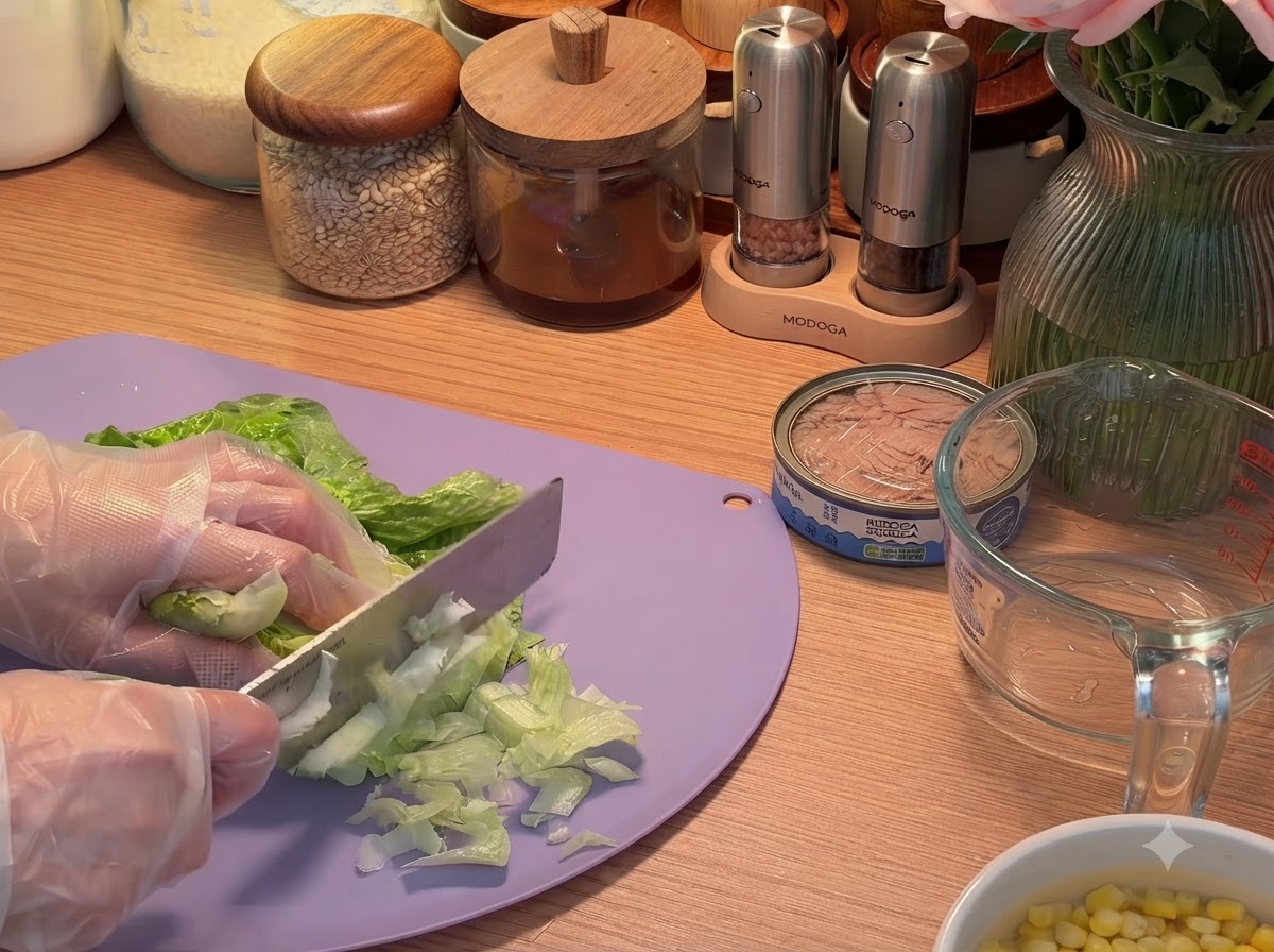 Lettuce leaves being sliced into shreds on a cutting board with a knife.
