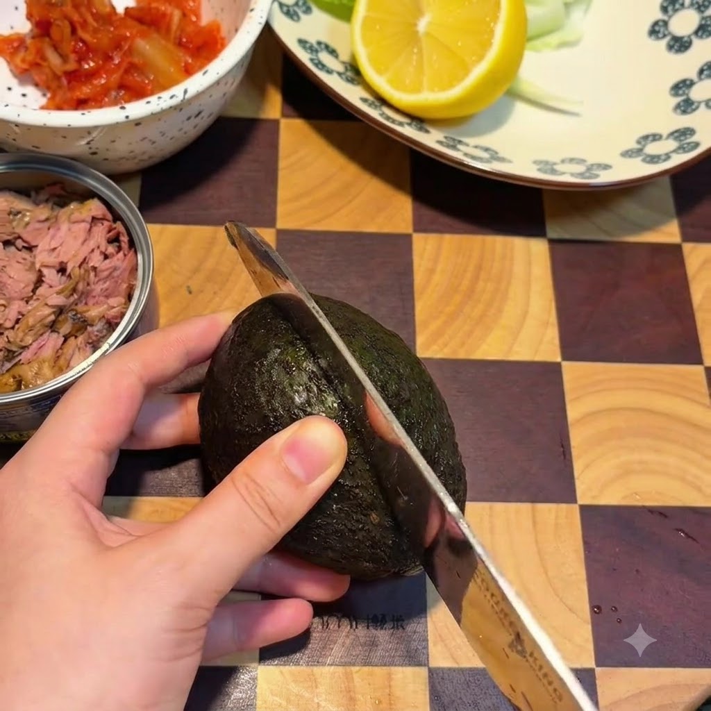 An avocado being sliced in half on a wooden cutting board with a knife.