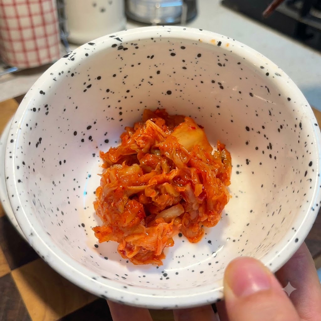 A white speckled bowl filled with a portion of bright red chopped kimchi.