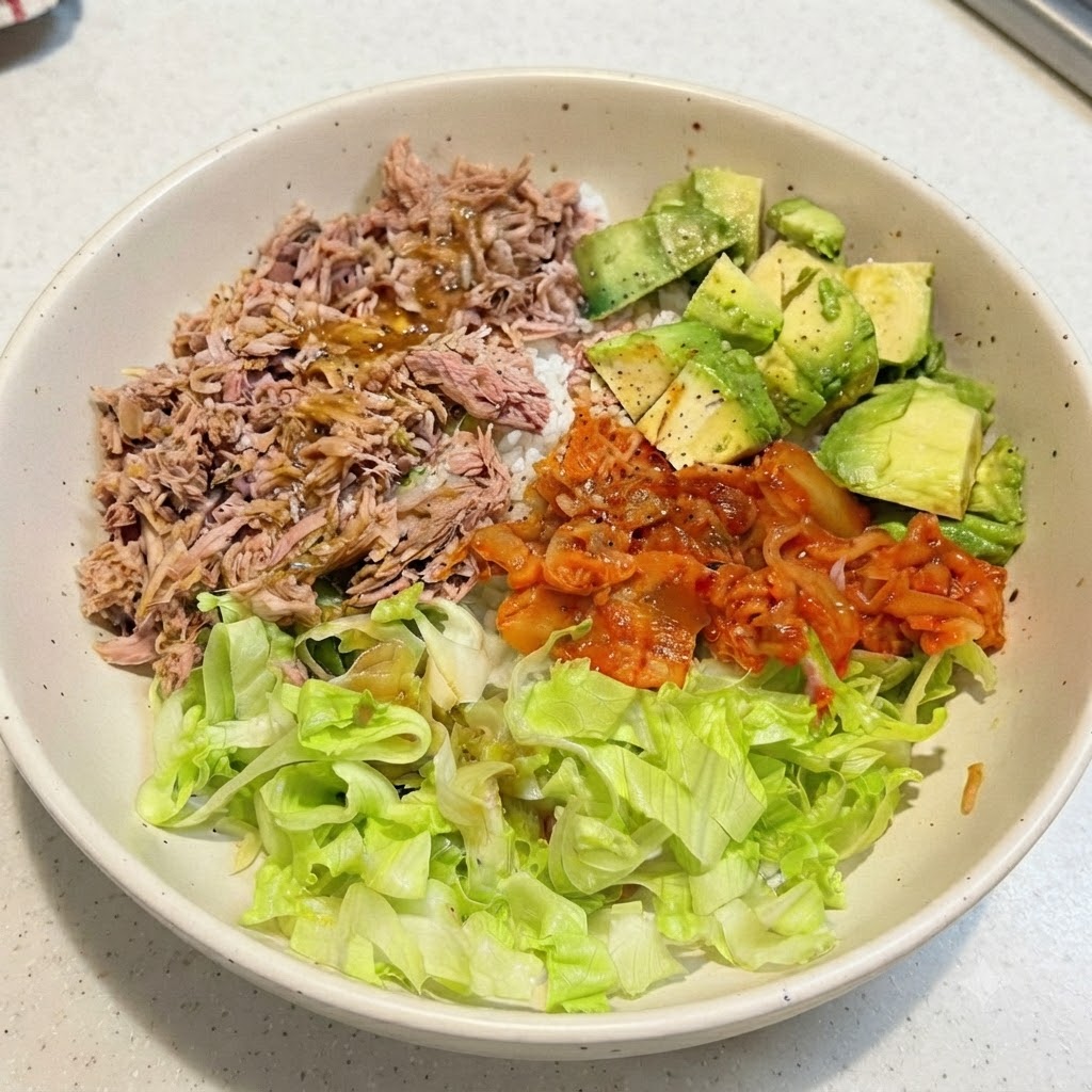 An assembled tuna avocado rice bowl with dressing drizzled over the top ingredients.