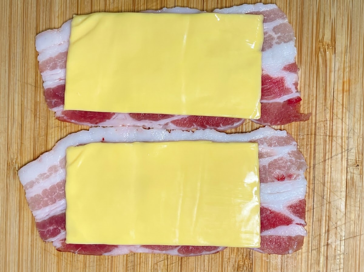 A portion of shrimp paste being squeezed from a piping bag onto the cheese and pork layers.