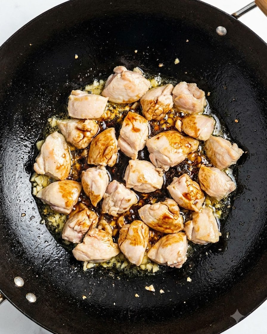 Pork ribs stir-frying in a wok with soy sauce and aromatics.