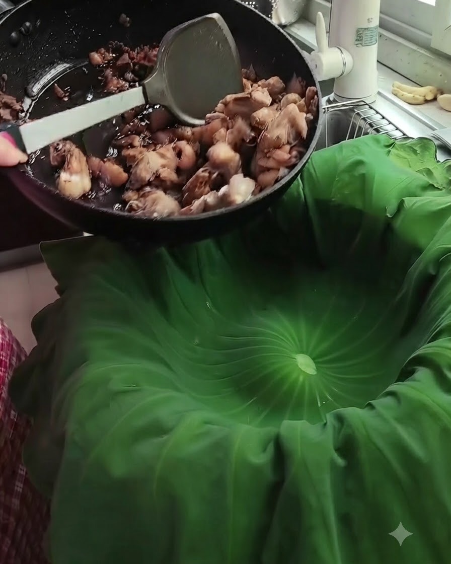 Stir-fried pork pieces being poured from a black pan into a large green lotus leaf lining a steamer.