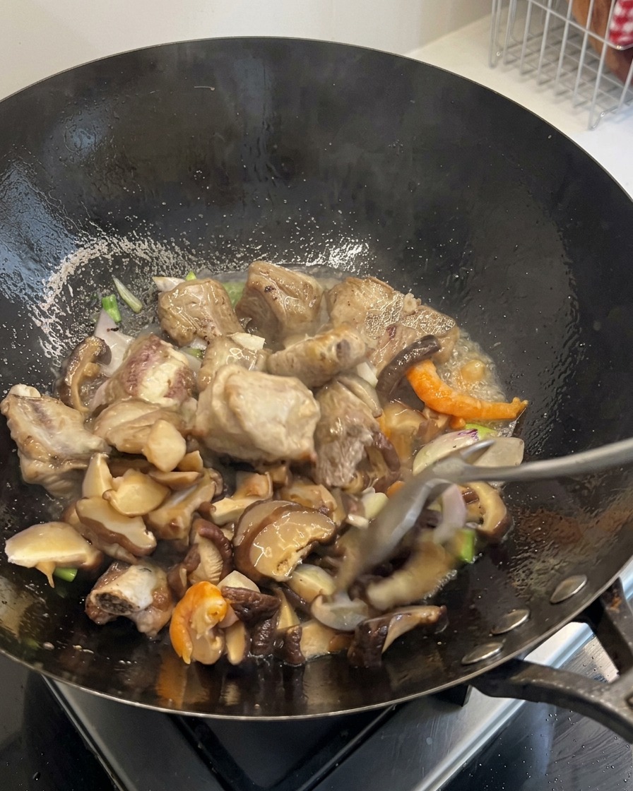 Diced carrots and corn kernels being mixed into the sizzling contents of the wok.