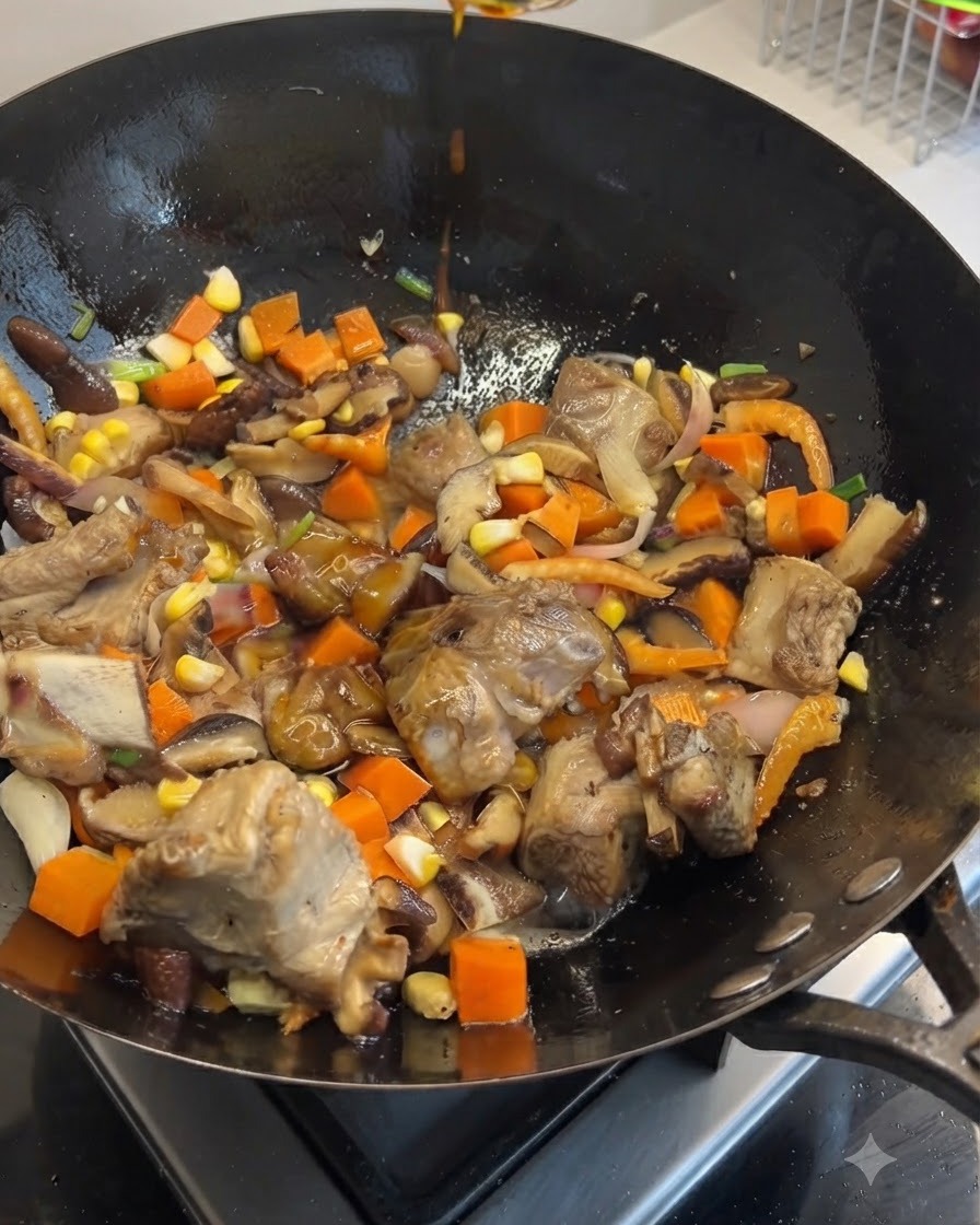Dark and light soy sauces being drizzled from above into a wok filled with stir-fried pork ribs, carrots, mushrooms, and corn.
