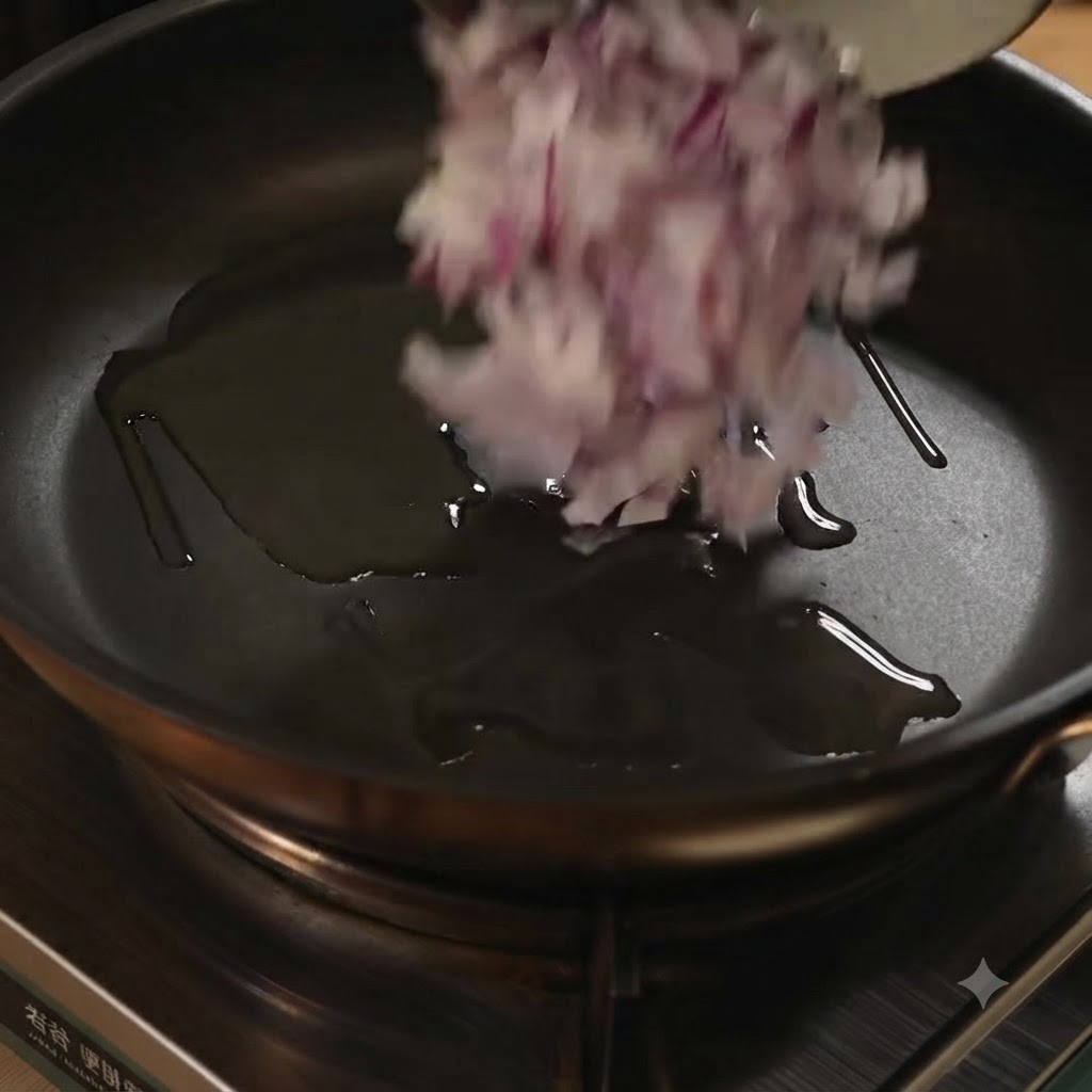 Chopped red onions being tossed into a frying pan with oil.