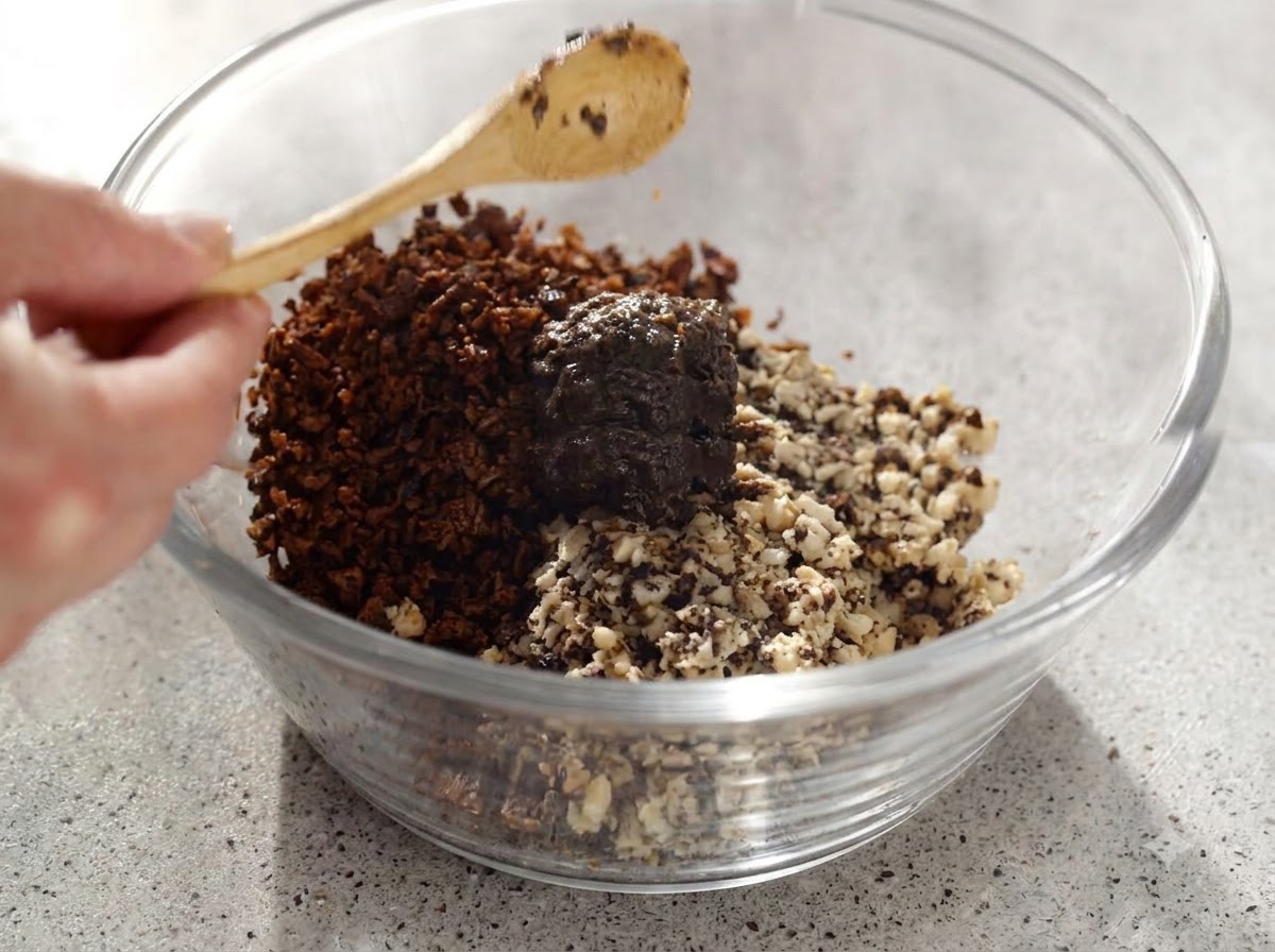 Truffle paste and chopped mushrooms being mixed thoroughly in a glass bowl with a wooden spoon.