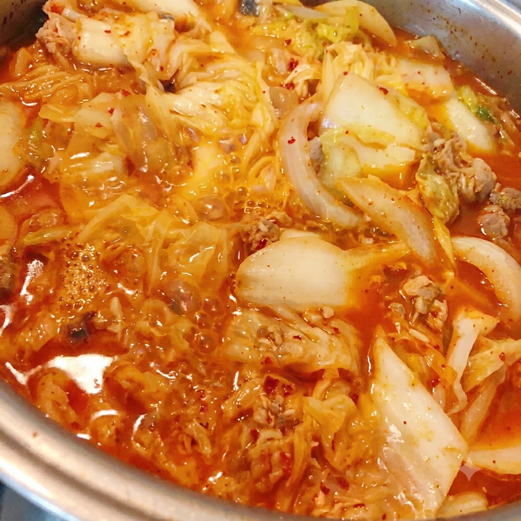 Chili powder being added into the simmering kimchi and tuna stew.