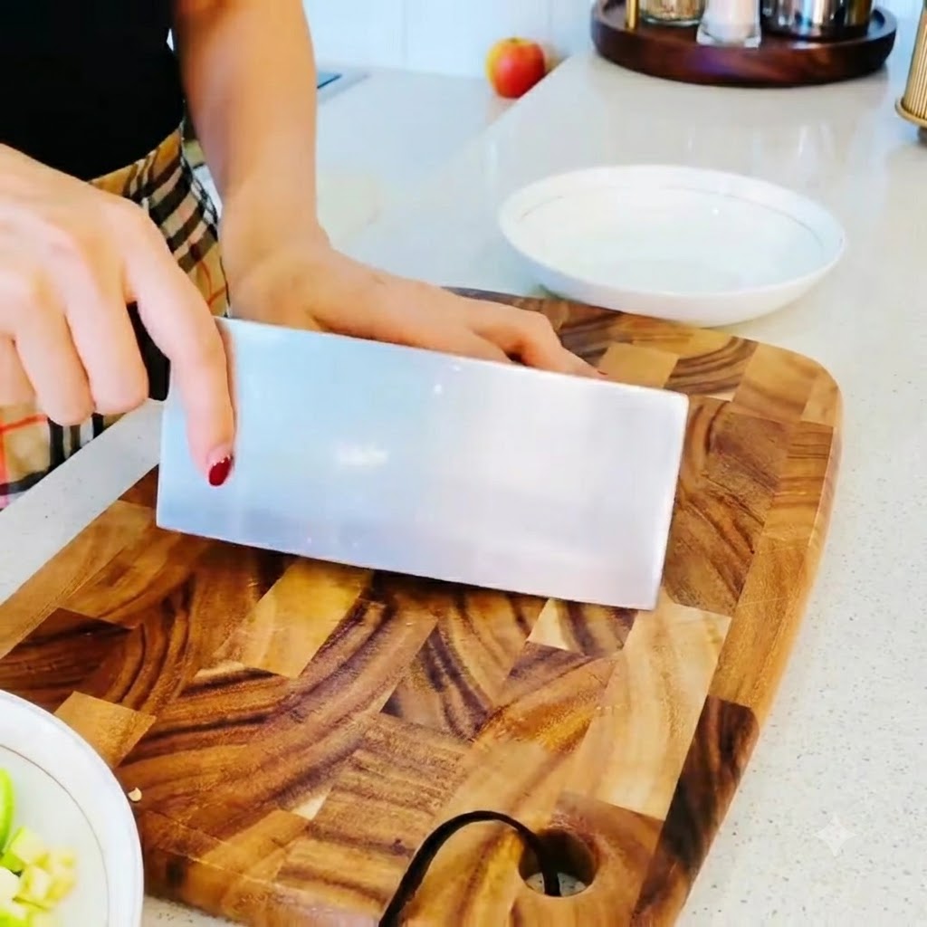 Enoki mushrooms having their root ends trimmed off cleanly on a wooden cutting board.