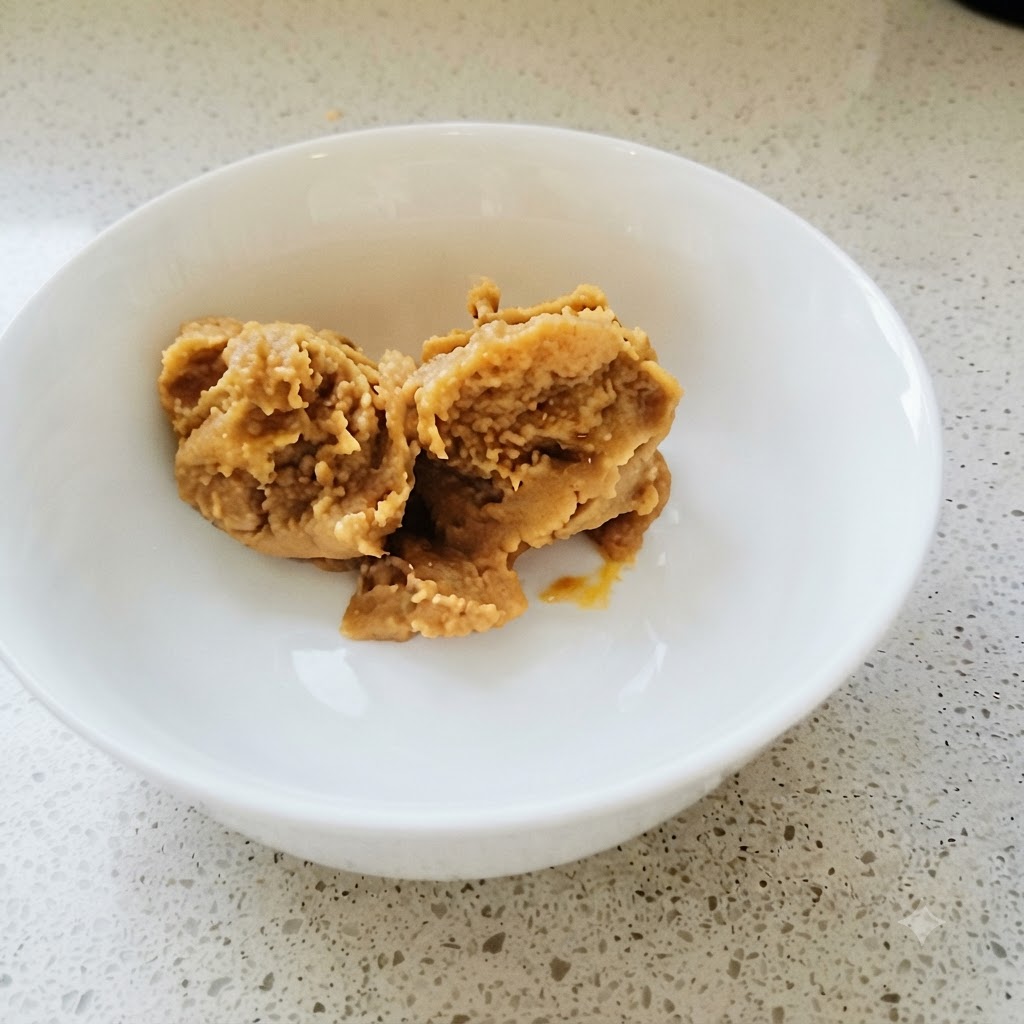 Korean soybean paste and chili paste being thoroughly mixed in a white bowl with a golden spoon.