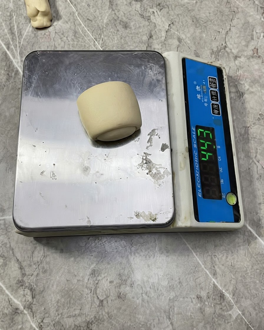 A small dough ball placed on an electronic digital weighing scale.