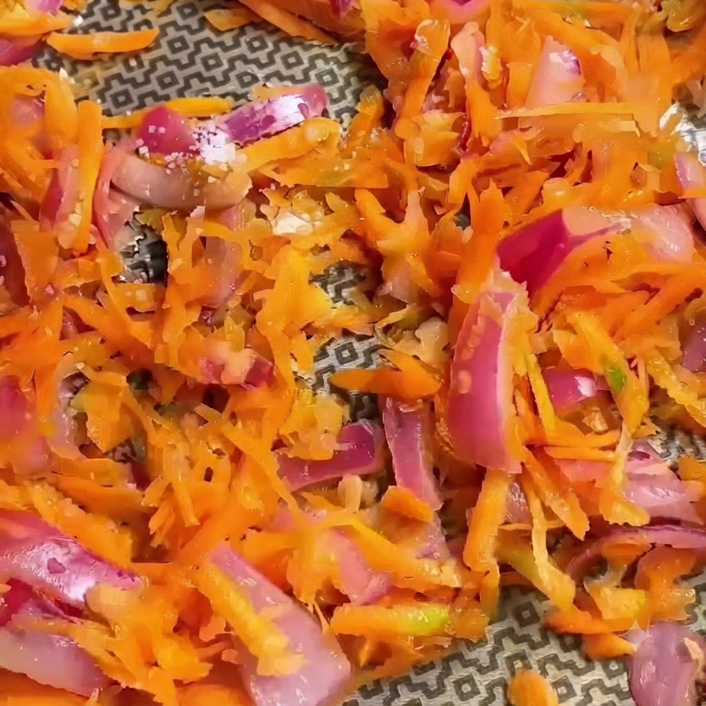 Close-up of seasoned shredded vegetables with visible spices sprinkled on top.