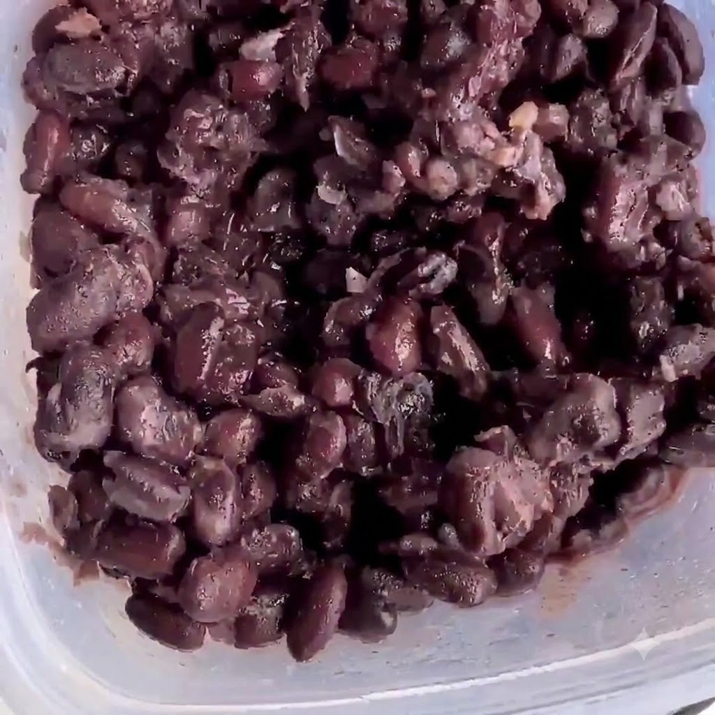 Cooked black beans inside a plastic container ready for mashing.