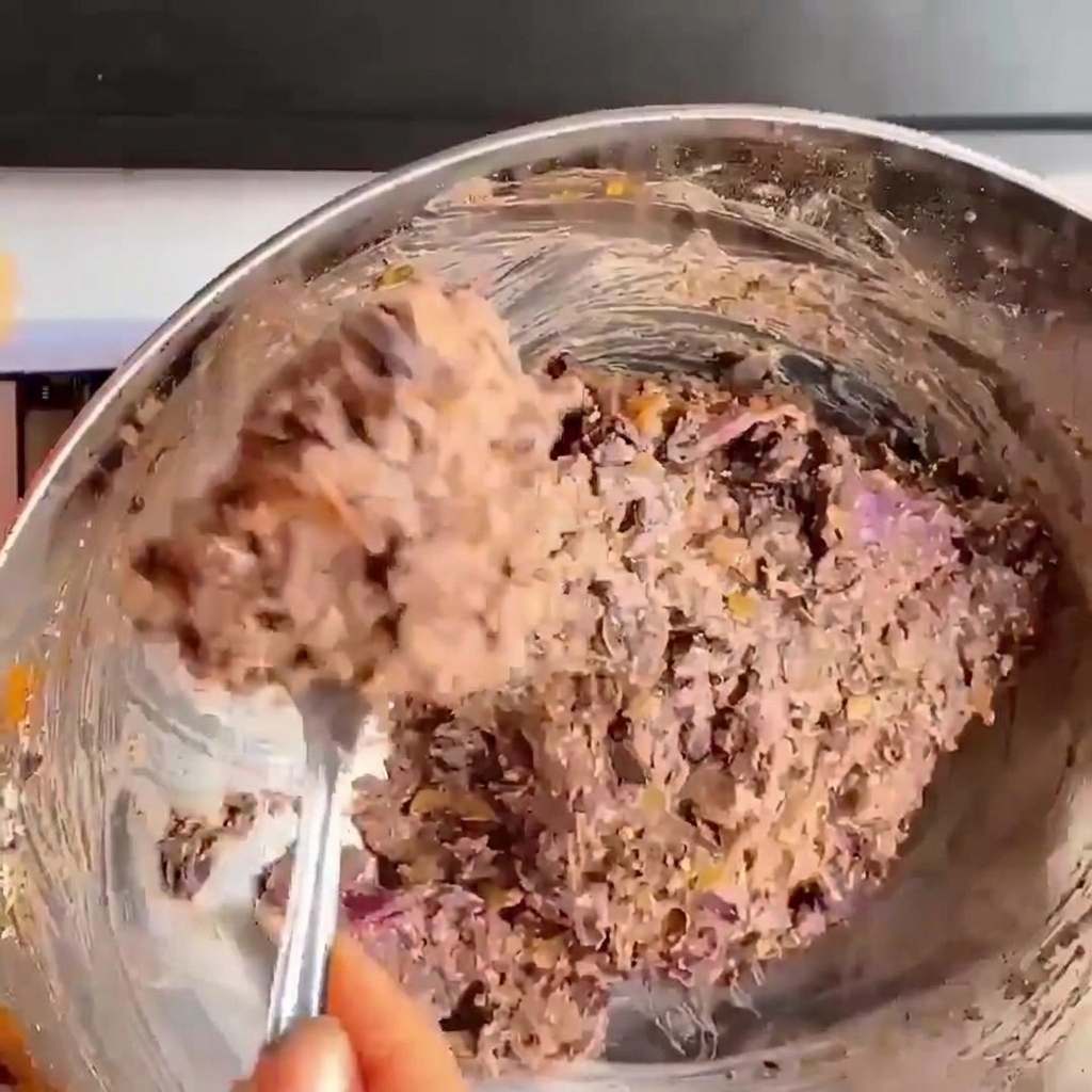 Close-up of hands pressing and shaping the black bean mixture into a round burger patty.
