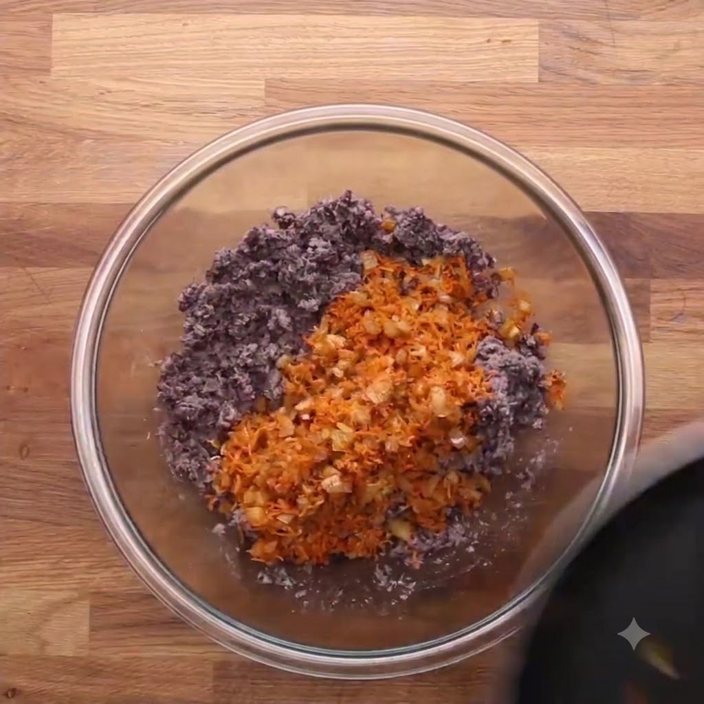 Quick oats poured into a glass bowl with mashed black beans and grated carrots.