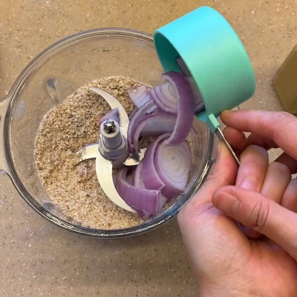 Sliced red onion and cooked black beans being poured into the blender cup.