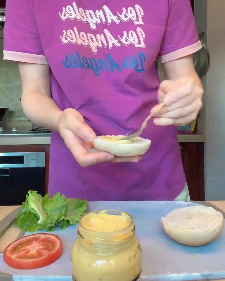 Hands wearing protective gloves shaping round burger patties on a tray.