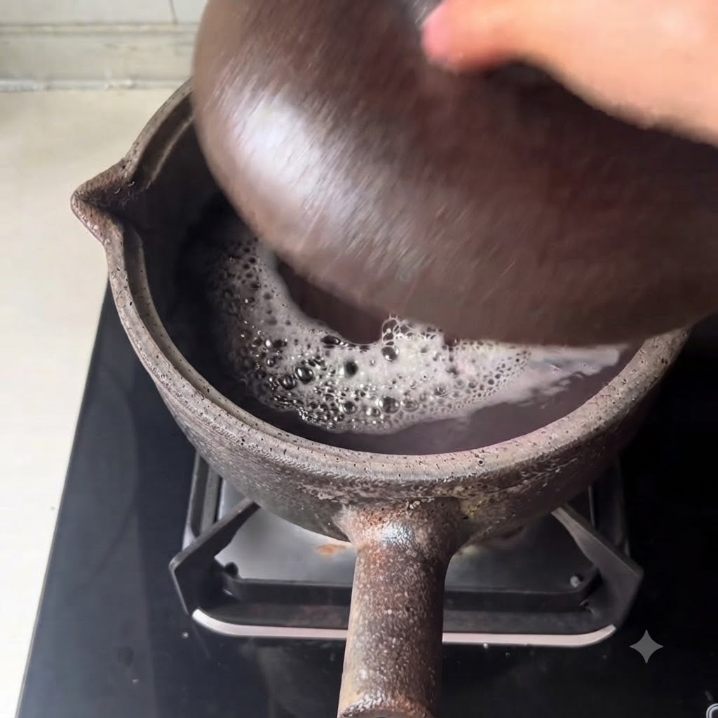A close-up view of the simmering dark broth and bubbling beans inside the earthenware cooking pot.