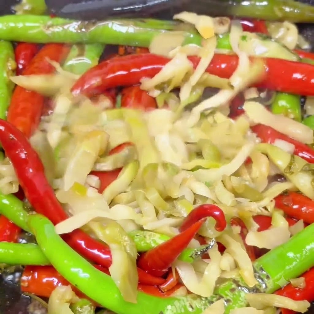 Pickled mustard greens mixed with blistered red and green chilies stir-frying in a hot wok.