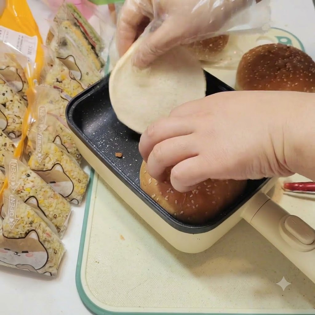 Burger buns being gently heated inside a black square flat-bottomed pan.