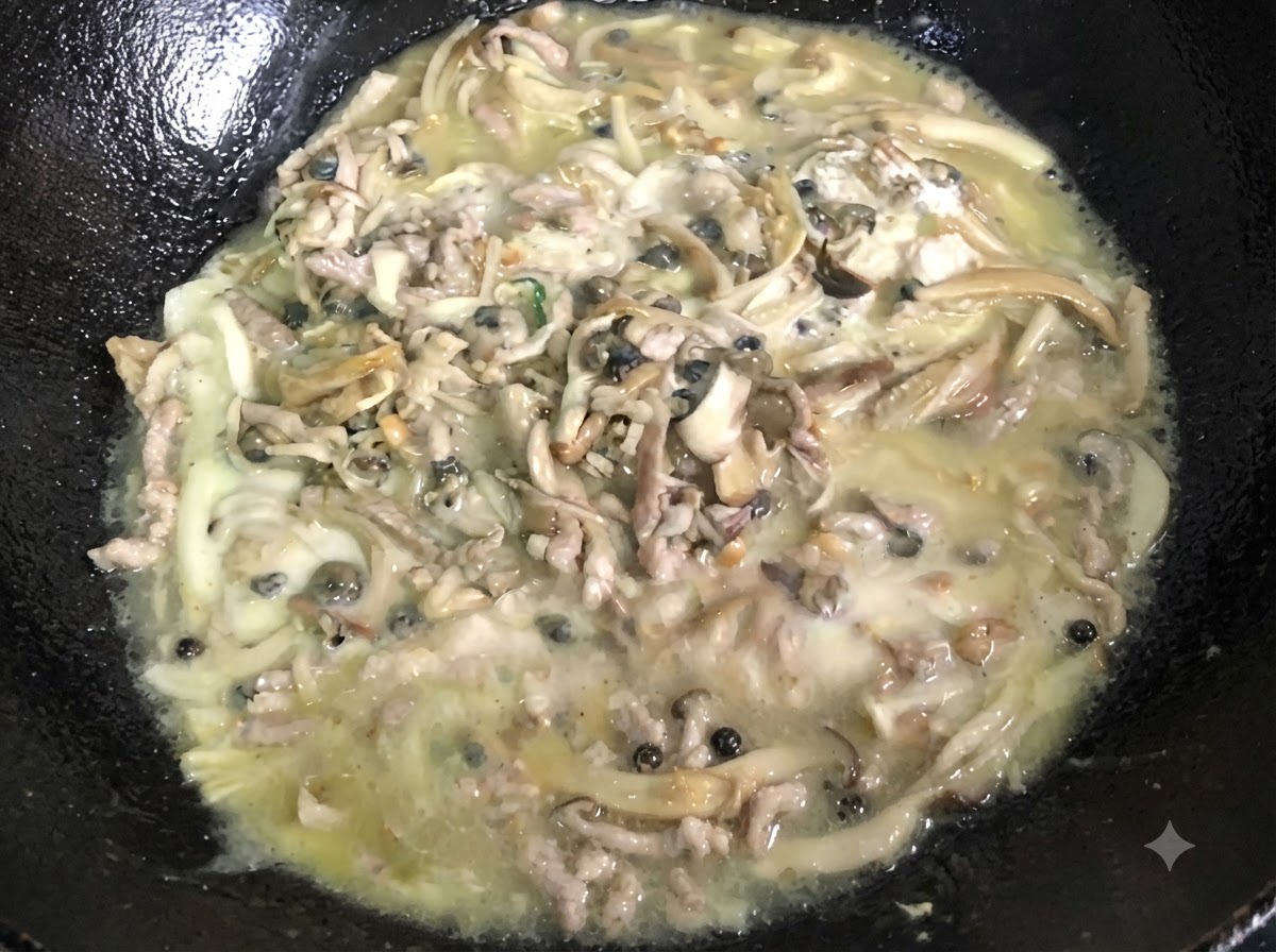 A thick, bubbling mixture being continuously stirred inside a black wok.