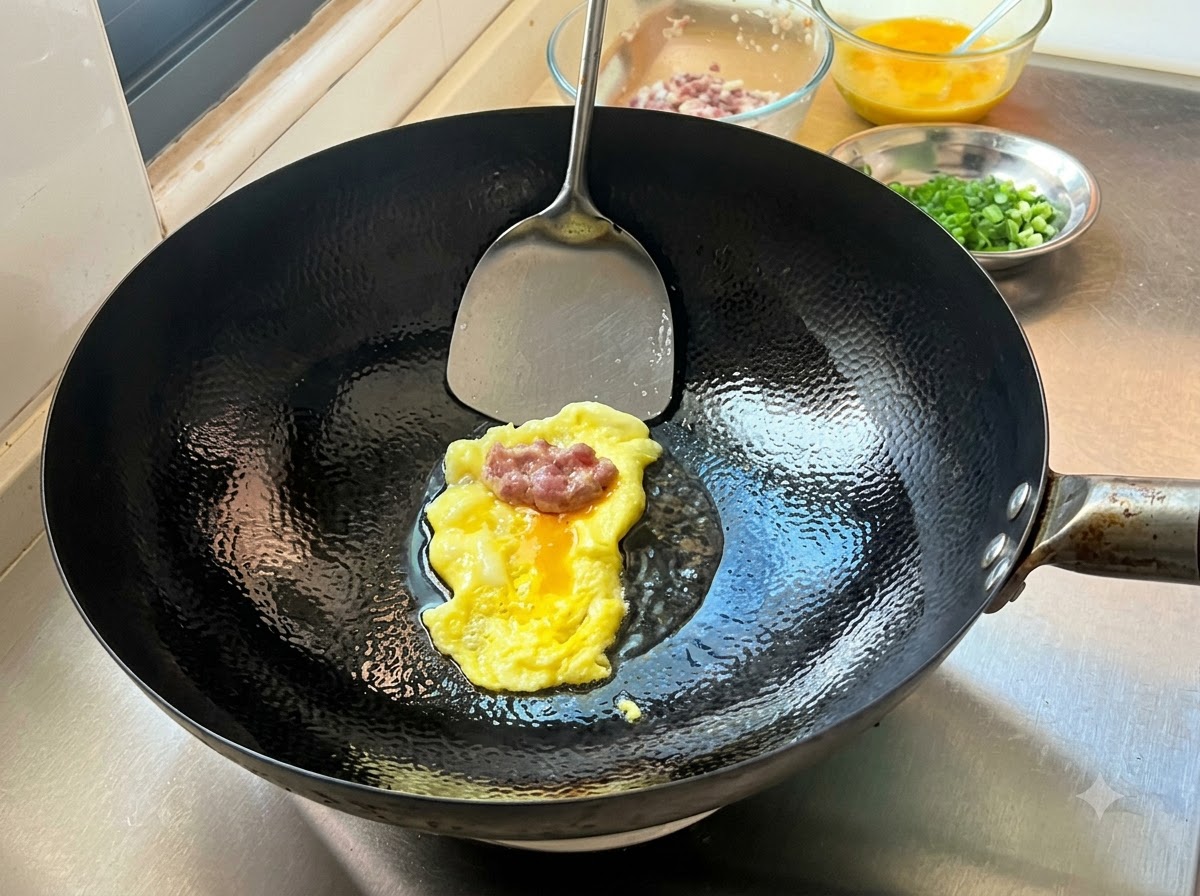 A portion of seasoned minced meat resting on a freshly cooked thin egg crepe in a hot wok, ready to be folded.