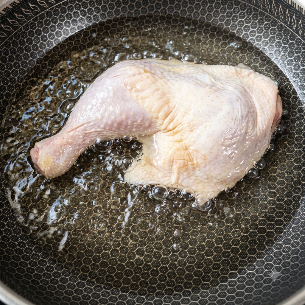 A large raw chicken thigh placed inside a pan filled with cold water starting to heat up.