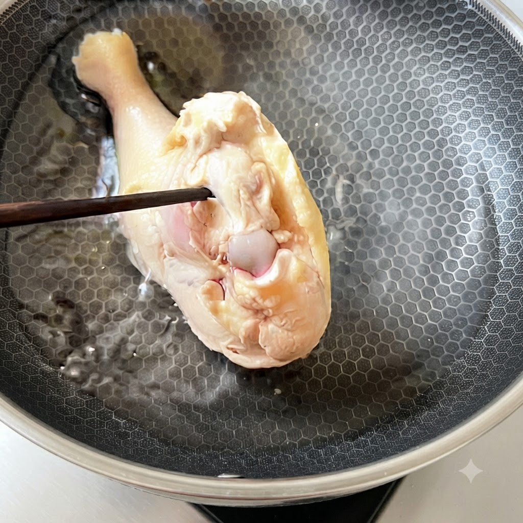A blanched chicken thigh being placed back into cold water inside a cooking pan.