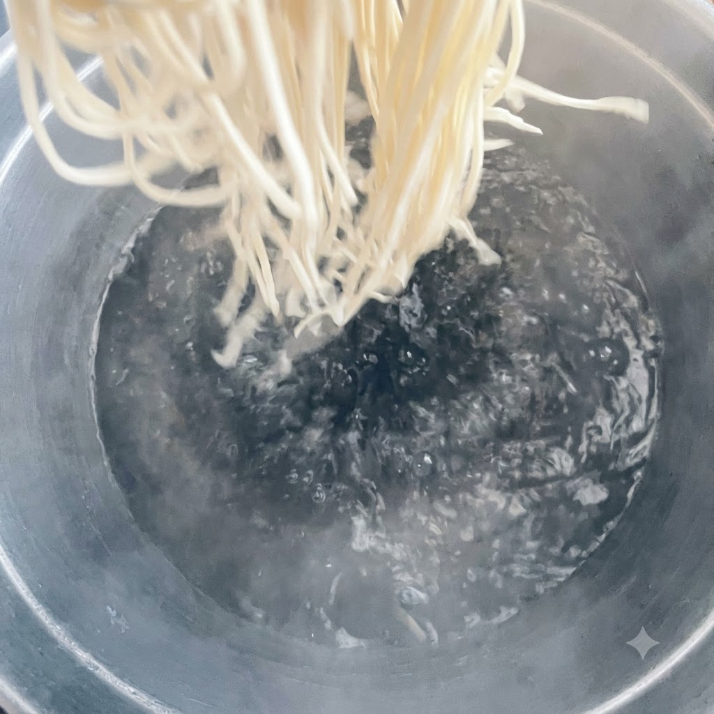 Noodles being dropped into a large pot of boiling water.
