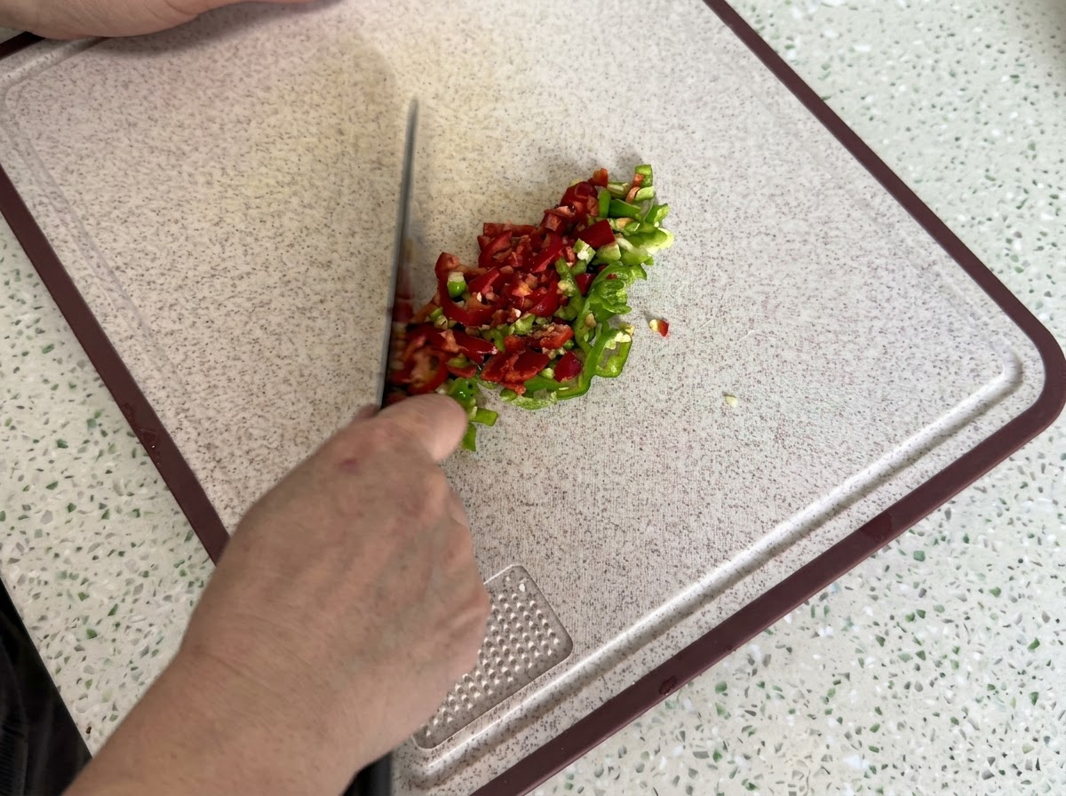 Red and green chili peppers finely sliced and diced on a clean cutting board.