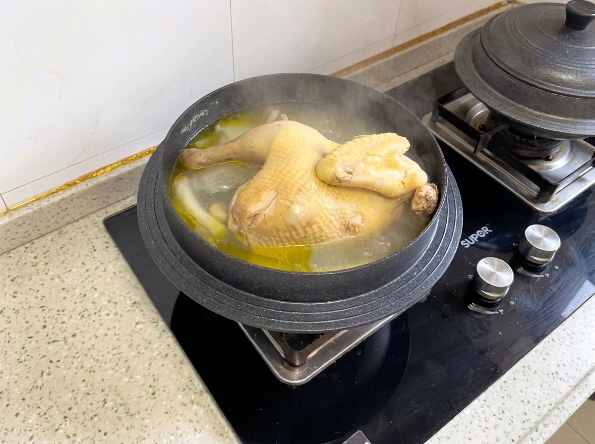 A cooked whole chicken simmering inside a pot before being portioned into pieces.