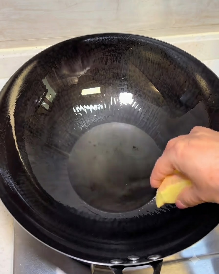 Ginger slices frying in hot oil in a dark wok.